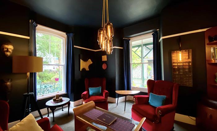 grey sofa against a black wall with yellow and red cushions, and mirrors above it